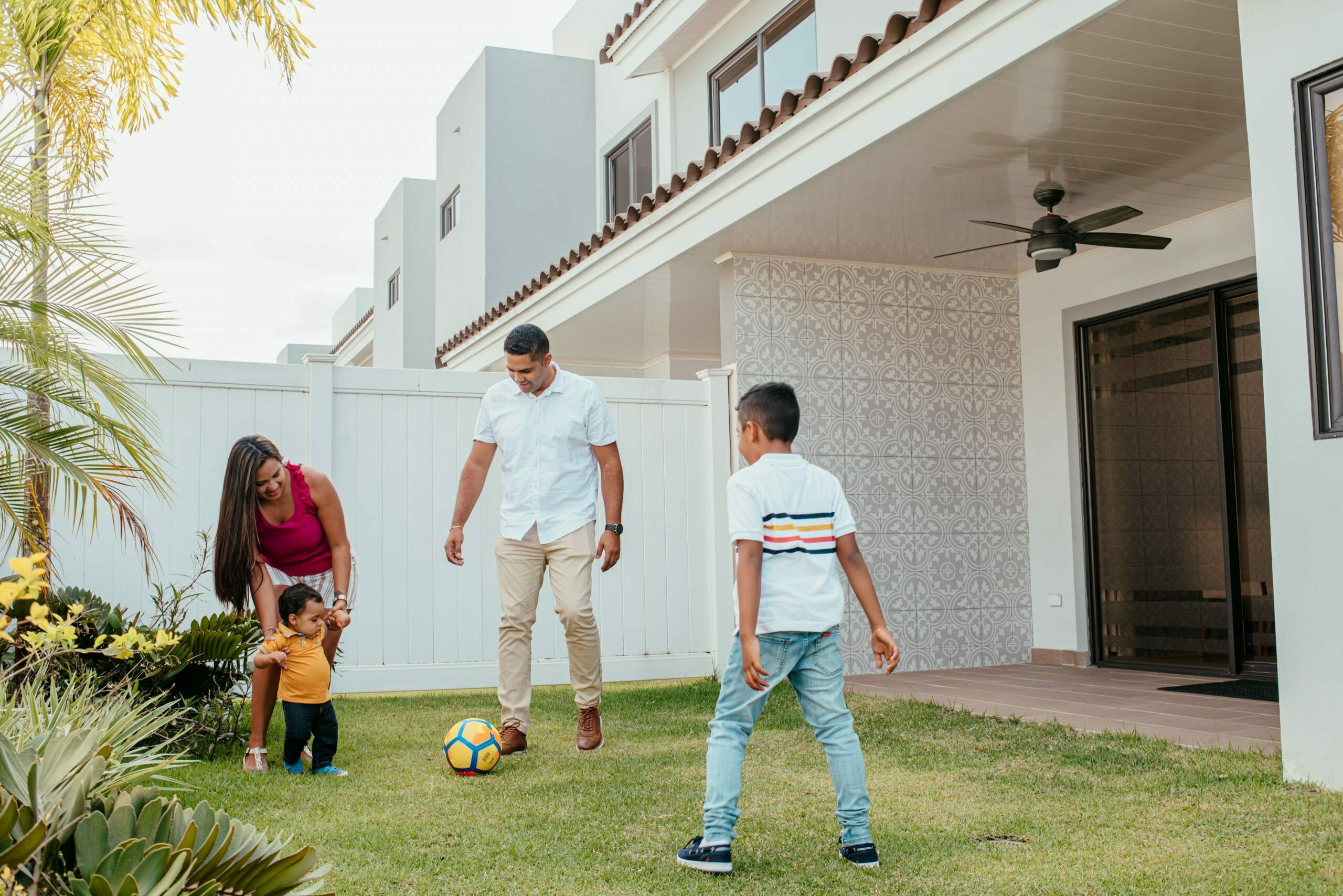 Madre, padre y 2 hijos jugando con la pelota en el patio de su casa en Paseo del Norte.