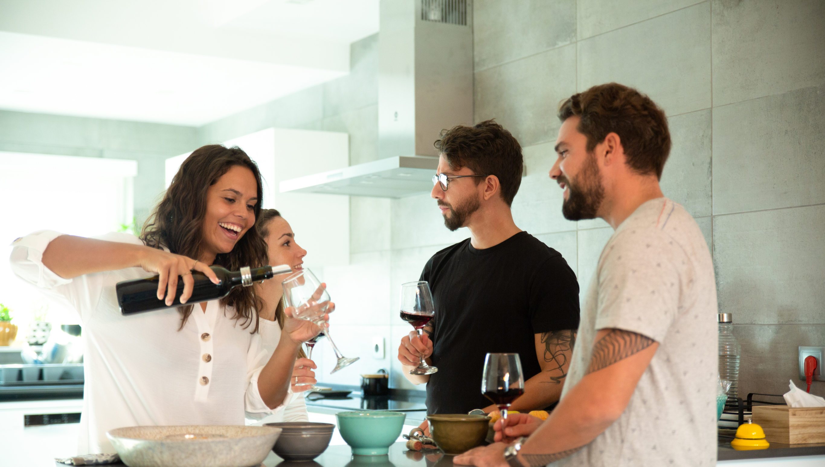 Dos parejas tomándose un vino dentro de la cocina relajados y riéndose 