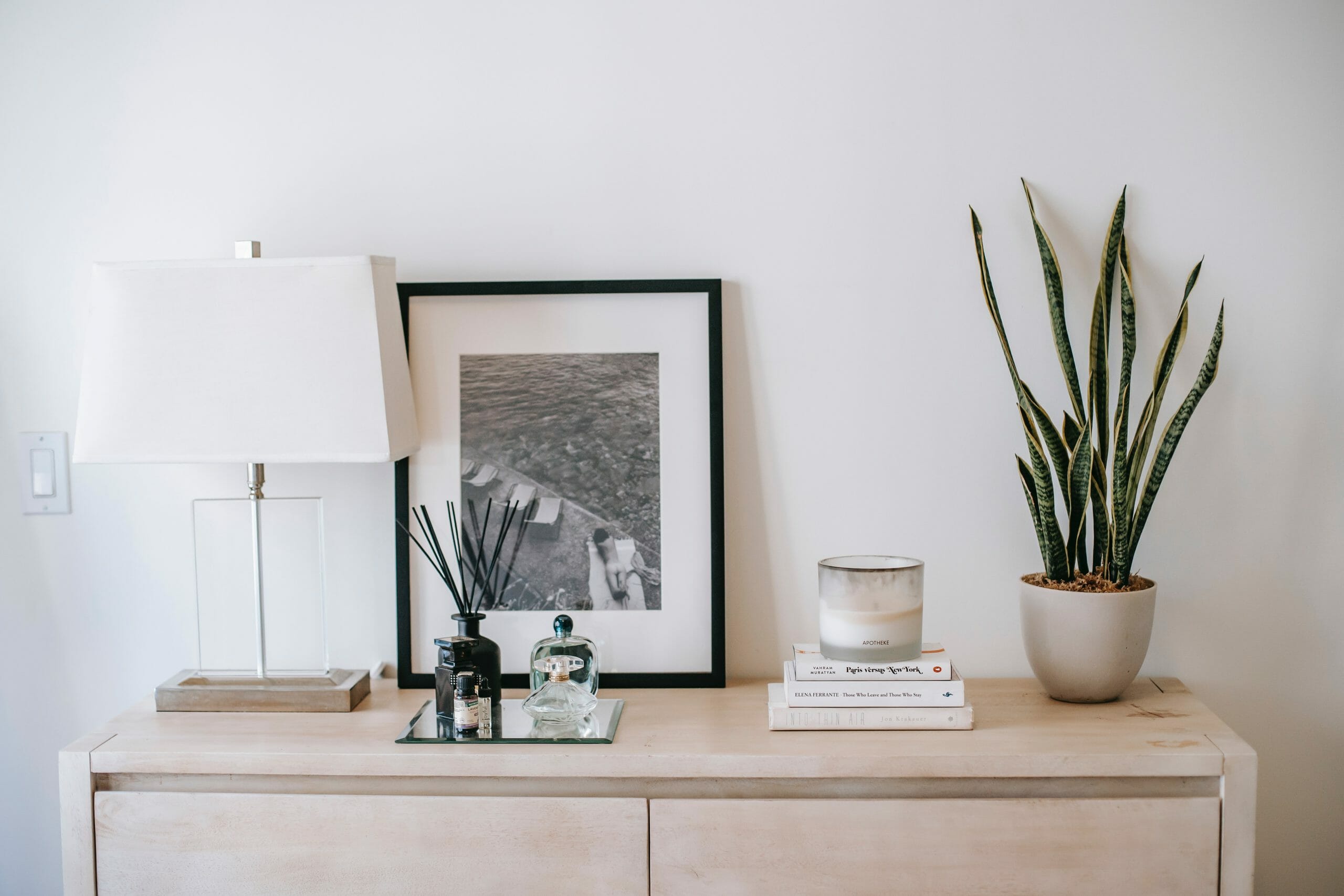 Mueble de casa con lámpara, cuadro y maceta con planta.