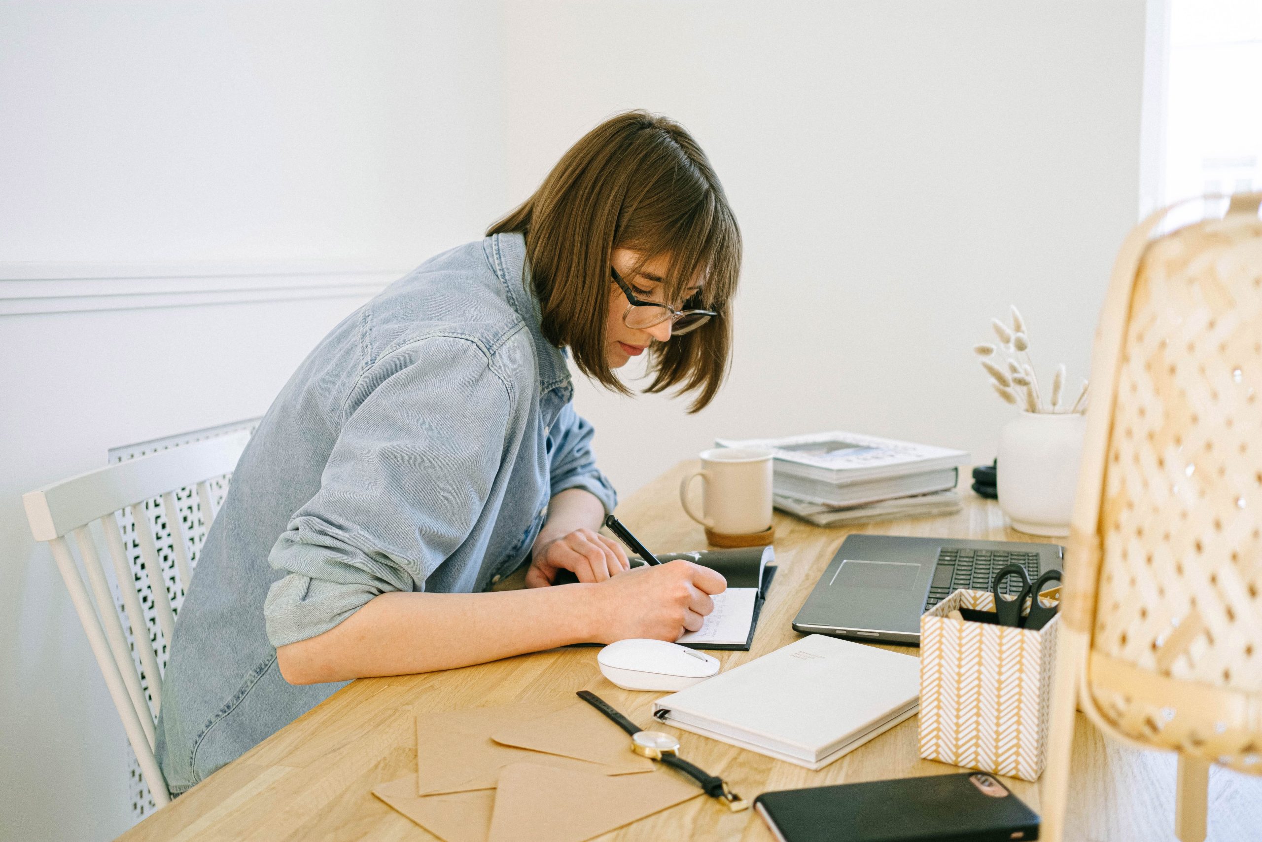 Mujer trabajando desde casa con laptop, agenda y una taza de café