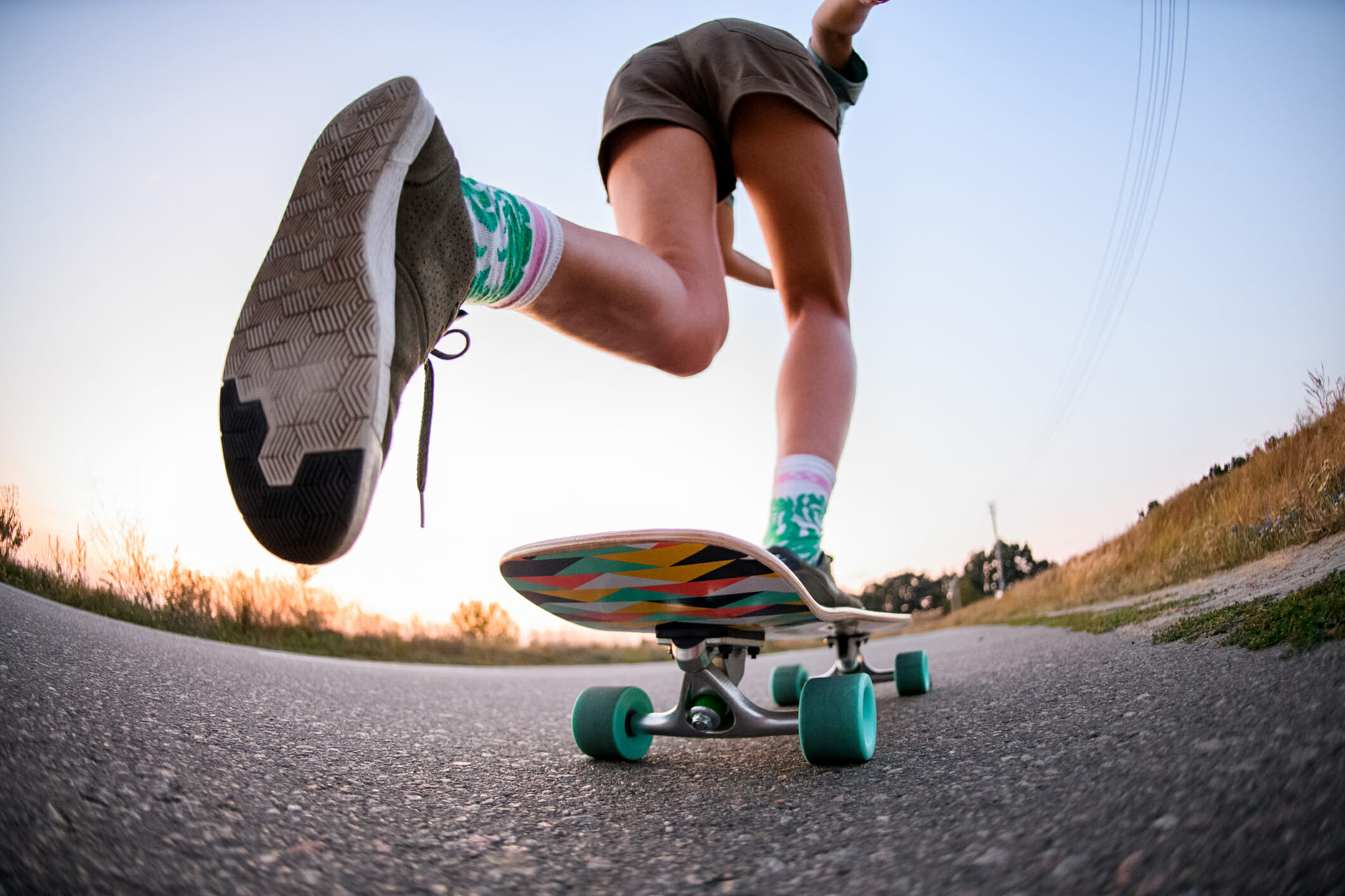 low angle view of girl who is riding on skateboard on the asphalt. Close-up of girl's legs