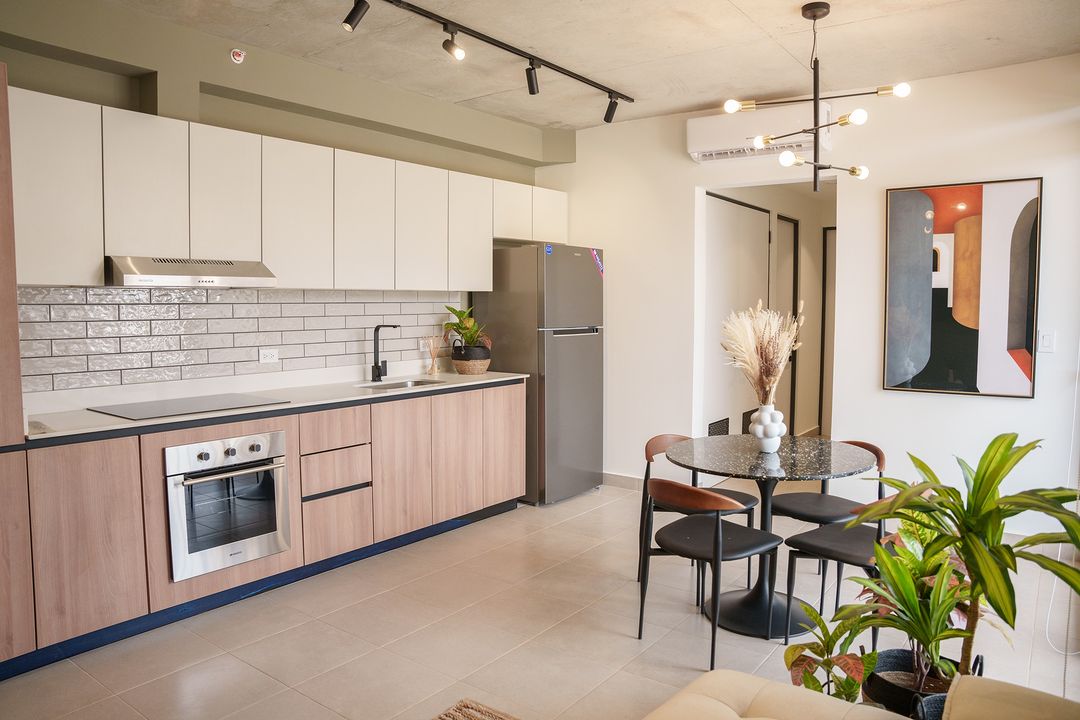 Espacio de concepto abierto de sala, comedor y cocina compartida en desarrollo inmobiliario de co-living
