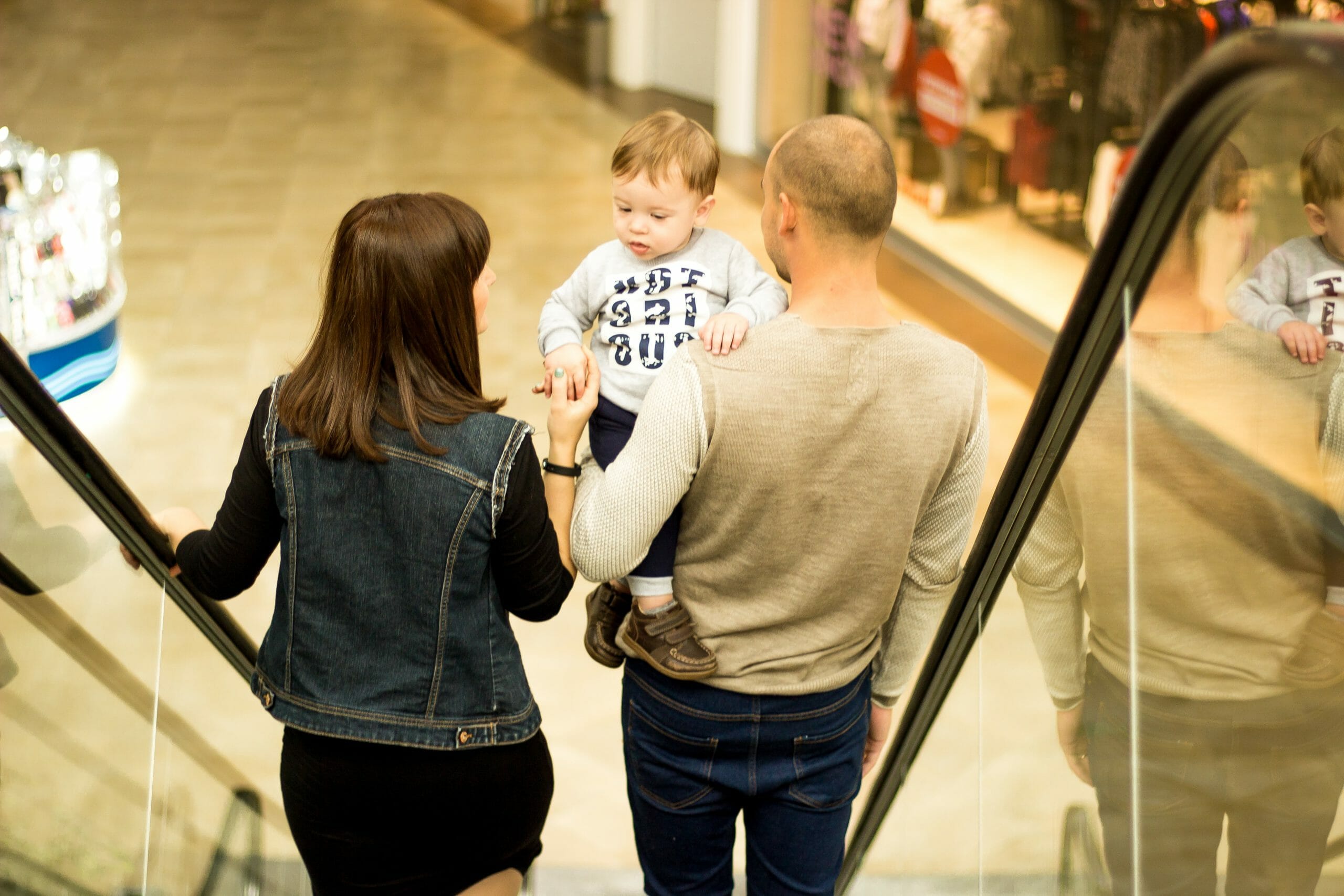 Familia bajando por una escalera eléctrica de un centro comercial mientras están de compras