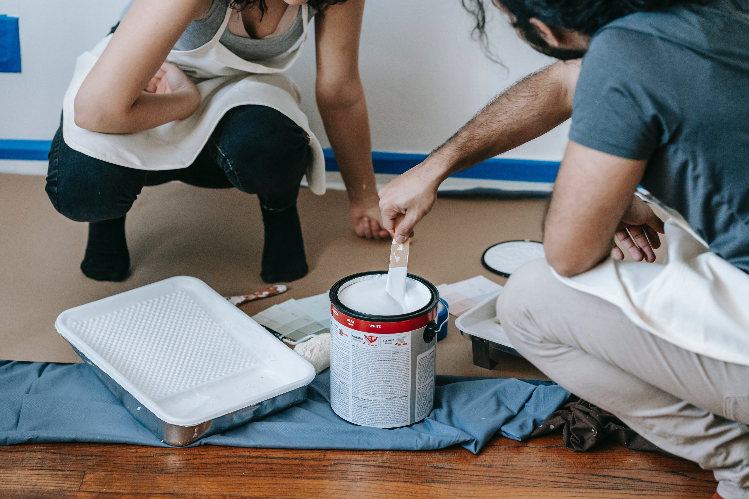 Pareja revolviendo una lata de pintura antes de pintar una pared en su hogar