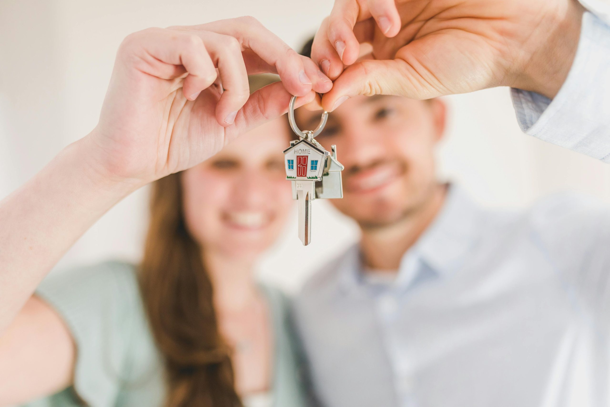 Feliz pareja sosteniendo y mostrando una llave de casa.