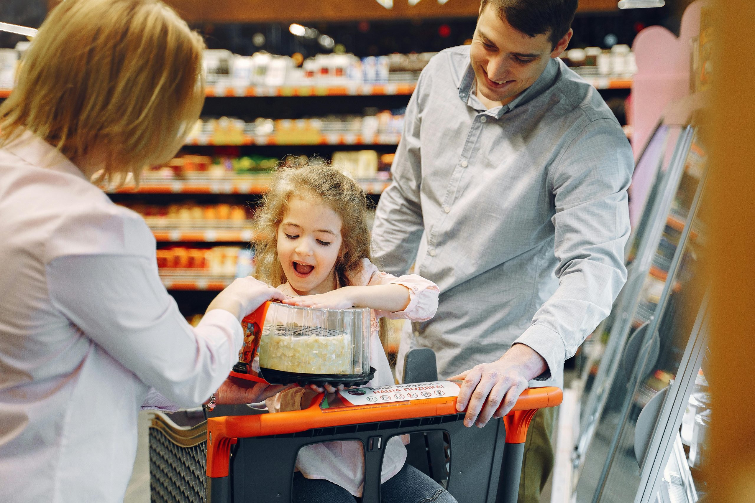 Niña feliz comprando un pastel con sus padres