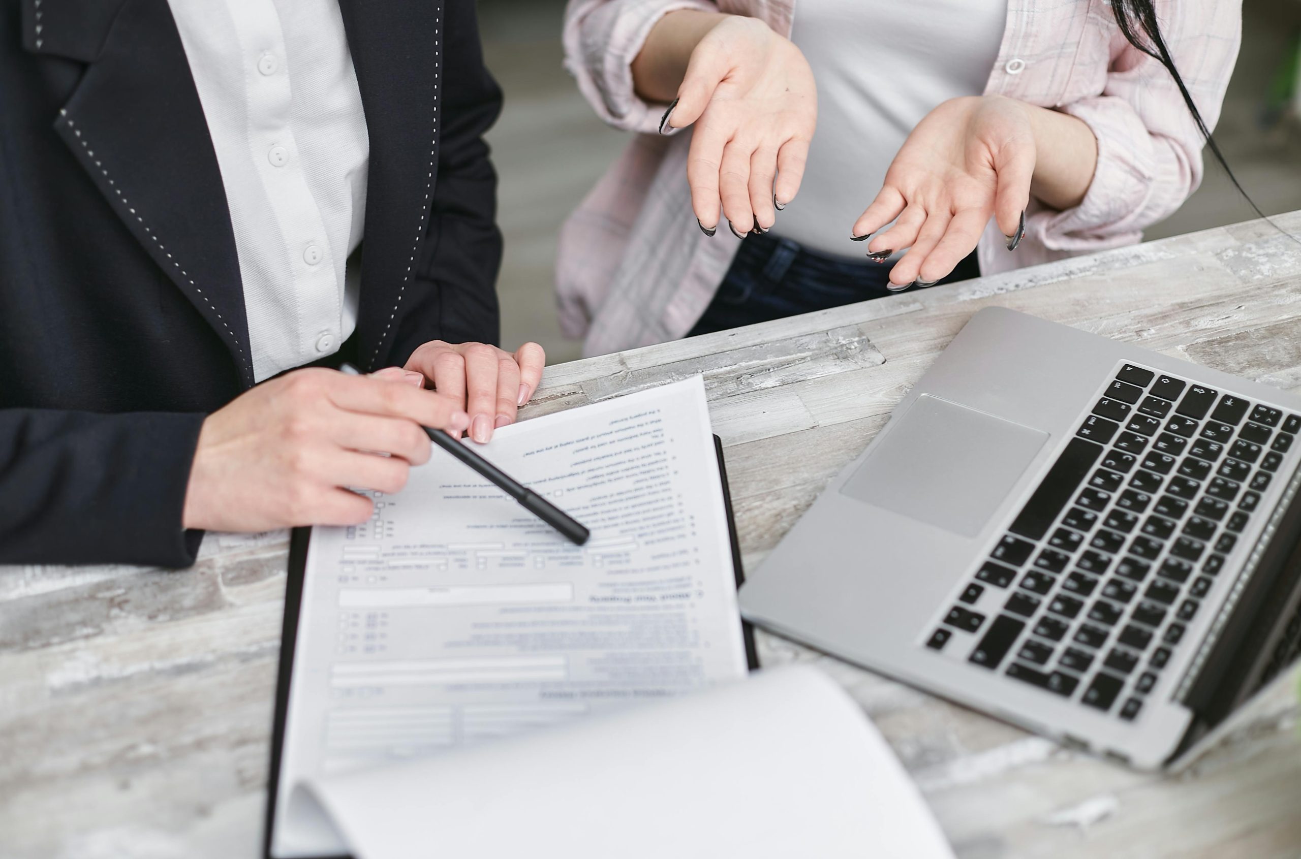 Dos personas frente a contrato y computadora calculando préstamos hipotecarios.