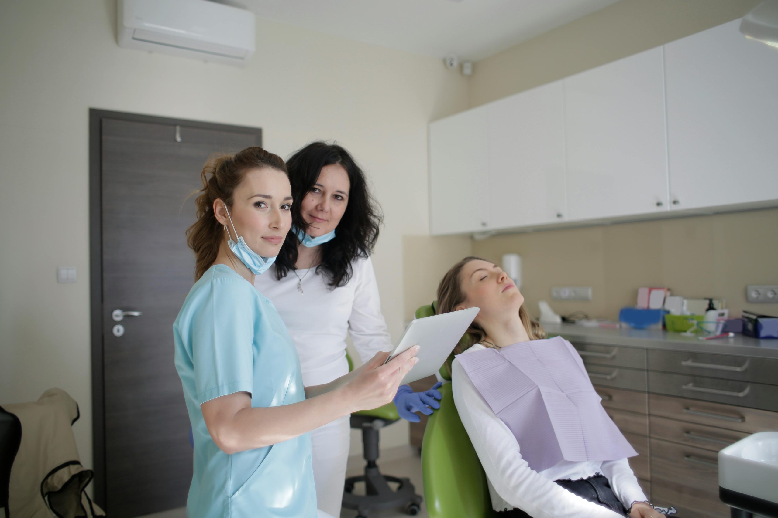 Personal médico con tableta y paciente acostado en clínica