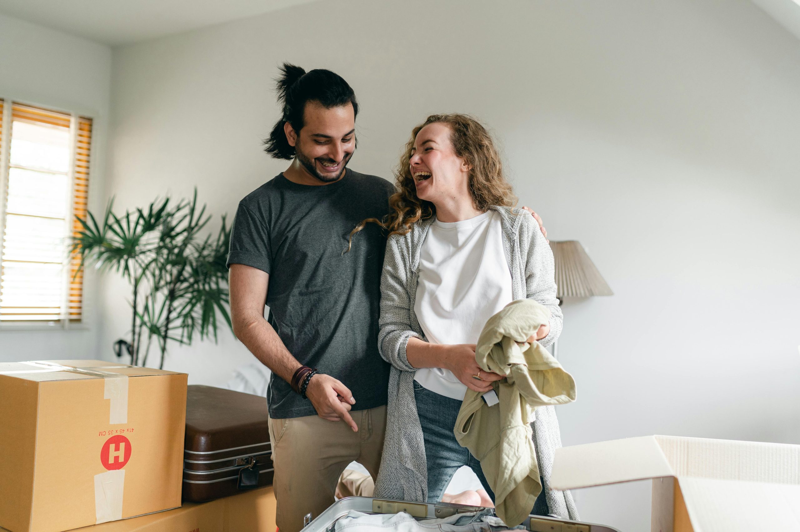 Pareja emocionada desempacando cajas en un nuevo apartamento