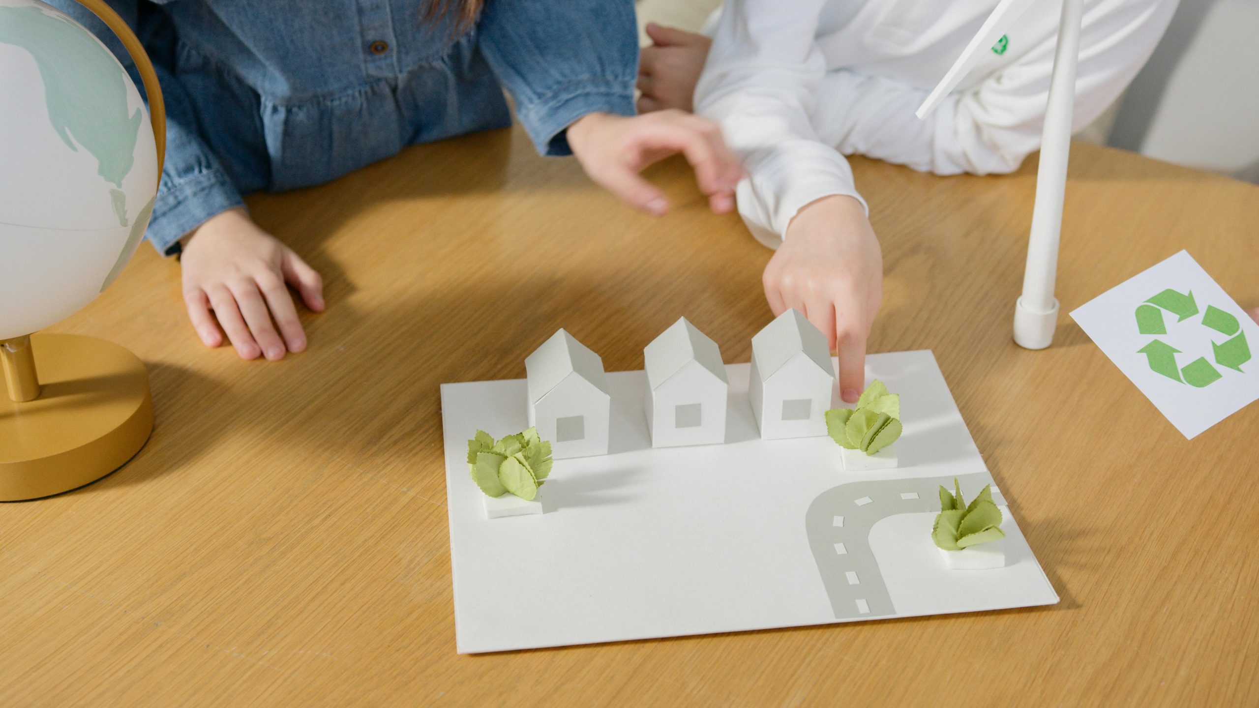 Niños jugando con tablero con casas, camino y plantas.