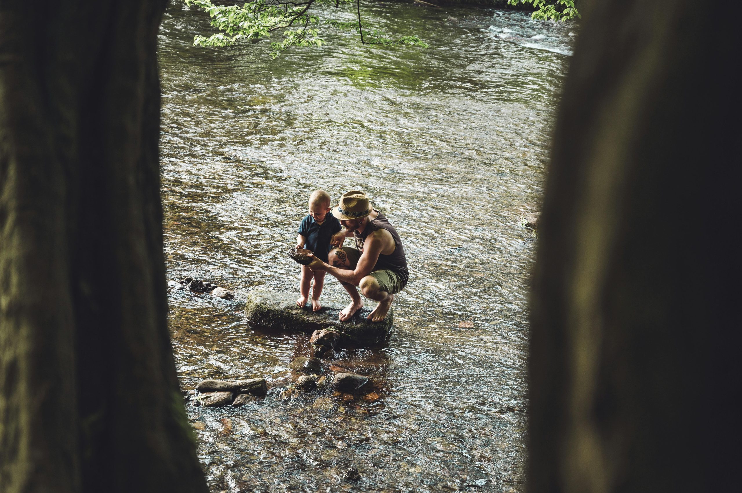 Padre e hijo explorando la orilla de un río.