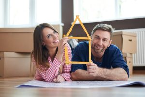 Pareja feliz con planos de remodelación de casa nueva