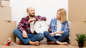 Pareja con cajas de mudanza y reloj