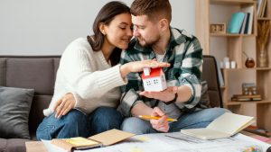Pareja con maqueta de casa analizando comprar una
